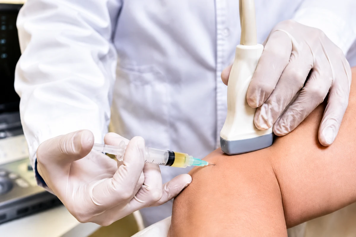 Doctor performing an ultrasound-guided PRP injection for tennis elbow to promote tendon healing and pain relief.