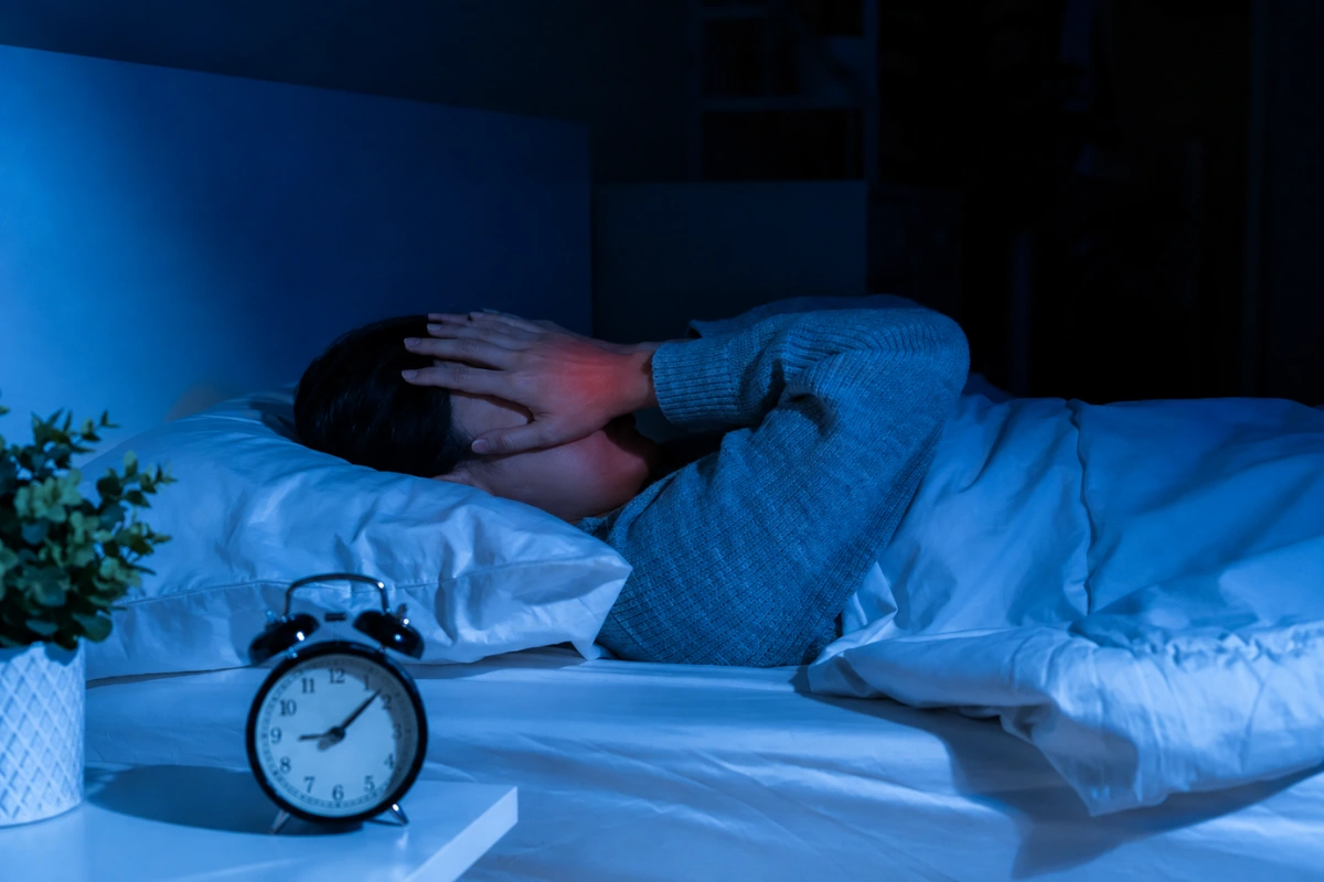 Woman sleeping in bed touching her aching wrist due to carpal tunnel symptoms waking her up at night