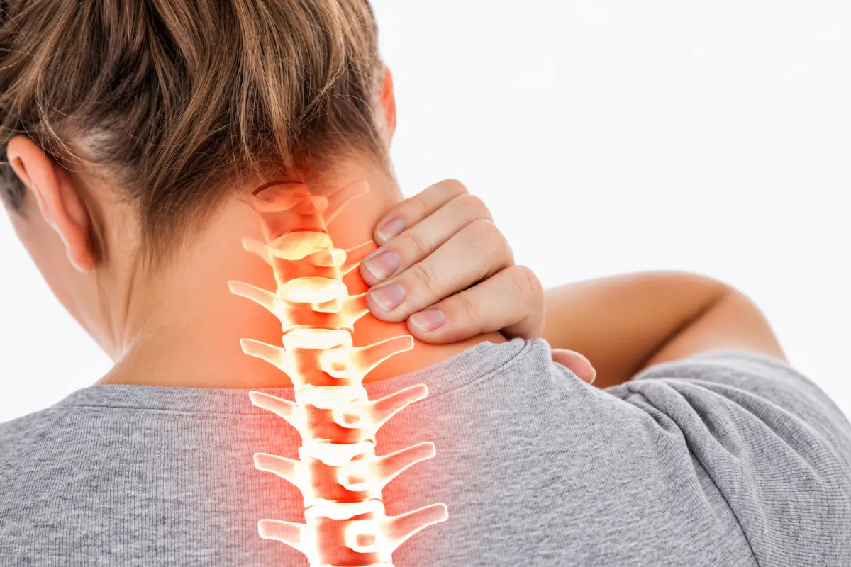 Person holding the back of the neck with a highlighted cervical spine illustrating nerve pain associated with cervical radiculopathy.